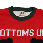 Red ugly sweater with white text and green collar, featuring a brand label.